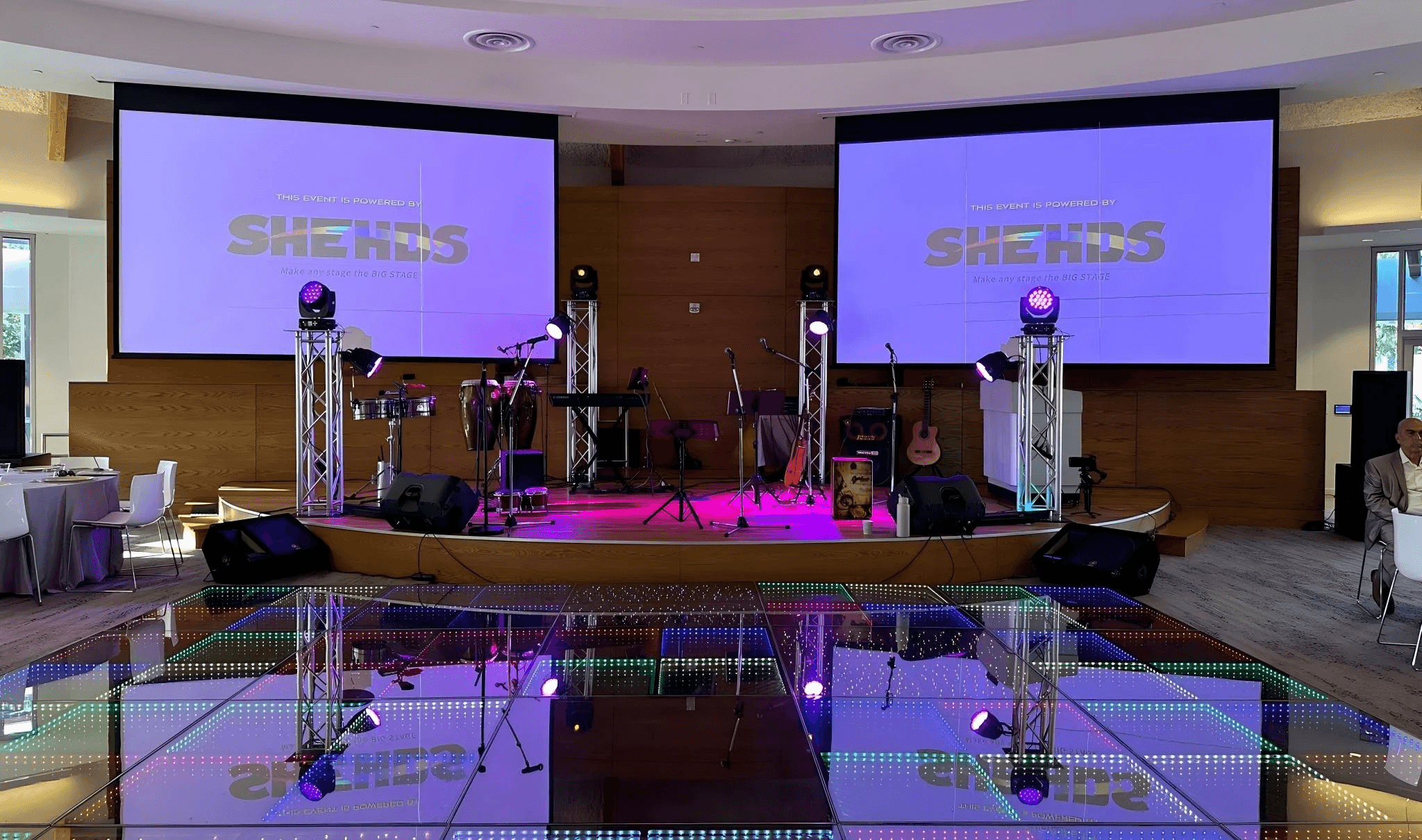SHEHDS stage lighting setup with moving head lights and LED dance floor at an indoor event venue