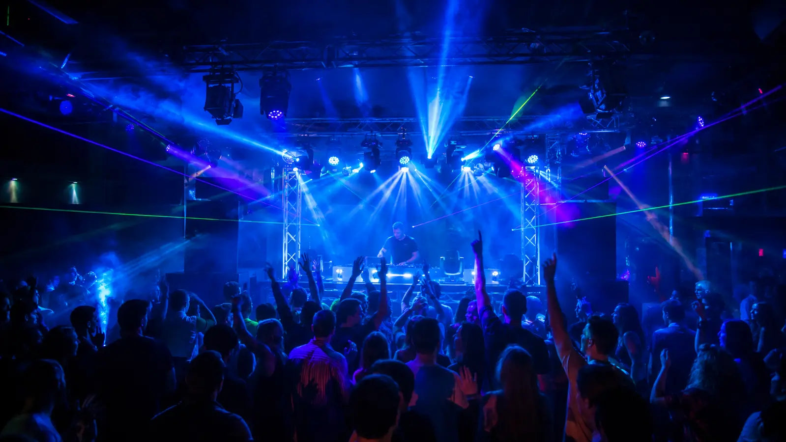  DJ booth with LED PARs, moving heads, and laser lights energizing a club dance floor