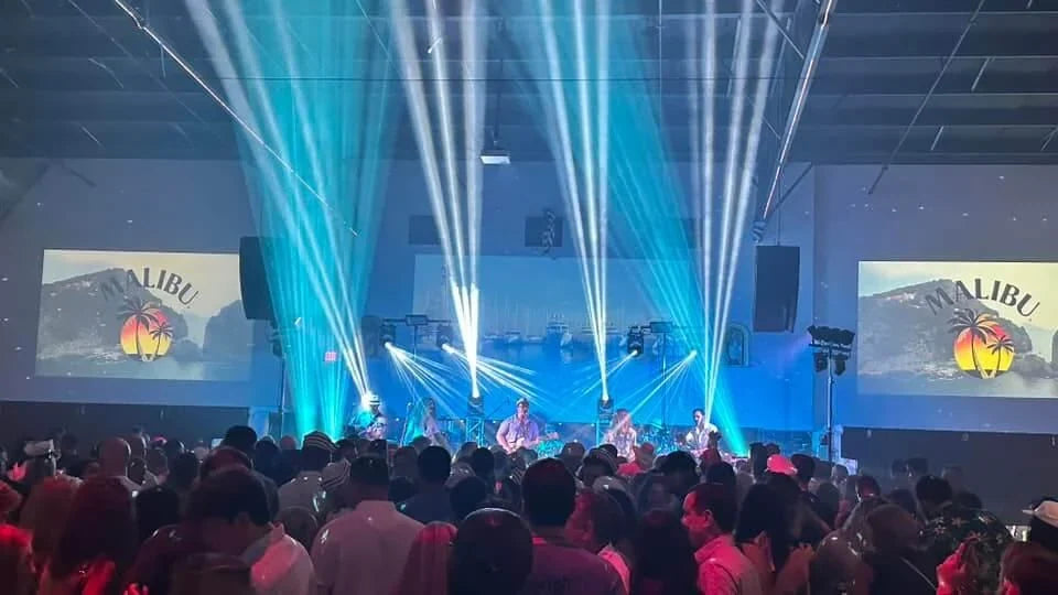 Moving head lights projecting blue and white beams above a live band